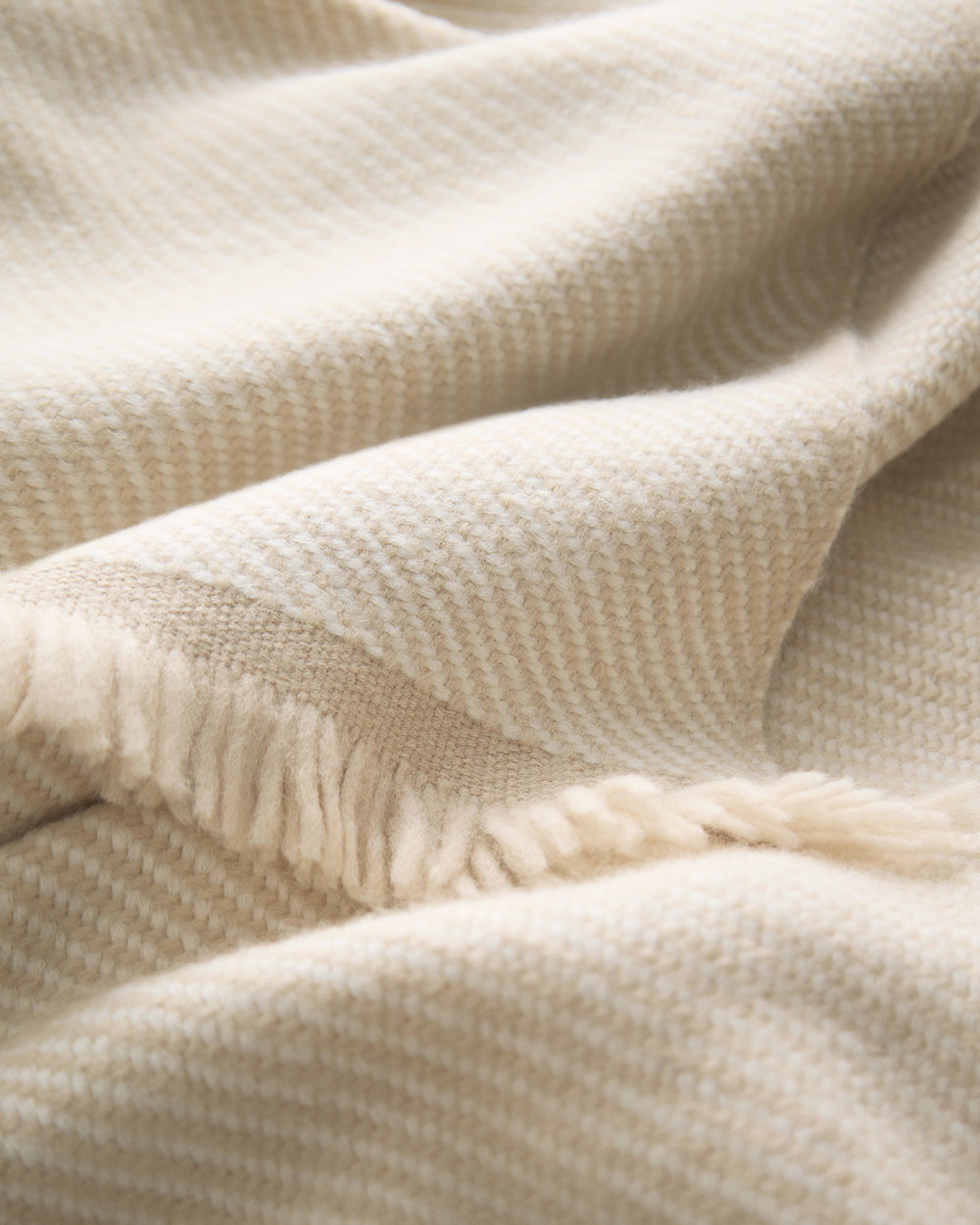 Two-Tone Alpaca Blanket Close-up of a folded blanket with fringe edges in a soft, textured pattern.