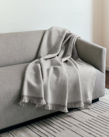 Sofa with a draped blanket and a rug on the floor.