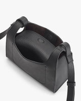 Open handbag with strap and button closure seen from above.