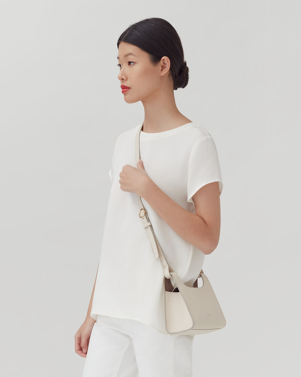 Woman standing and holding a shoulder bag