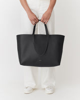 Person holding a large tote bag while standing.