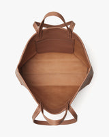 Top view of an open, empty leather tote bag with handles.