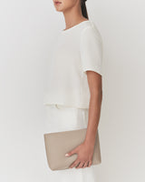 Person in a white outfit holding a clutch bag.