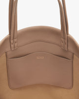 Close-up of a handbag with a brand logo on the front pocket.