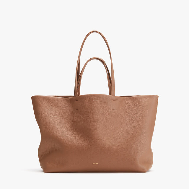 Large leather tote bag standing upright against a white background.