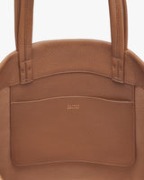 Close-up view of a handbag with a brand logo on the front pocket.