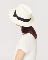 Person wearing a wide-brim hat with a ribbon, seen from behind.