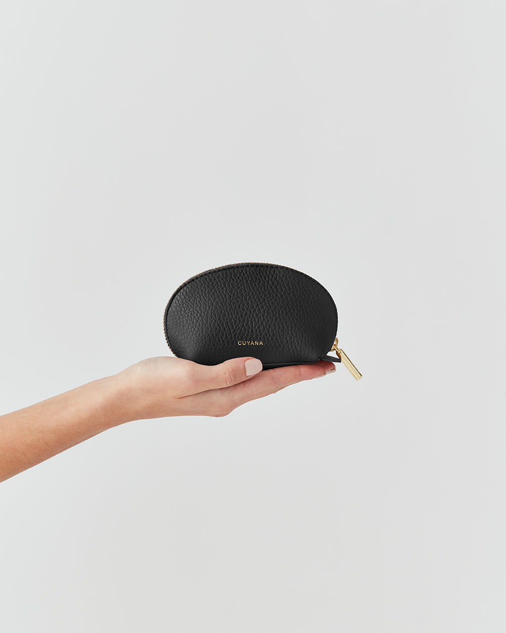 Hand holding a small zippered case against a plain background.
