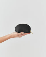 Hand holding a small zippered case against a plain background.
