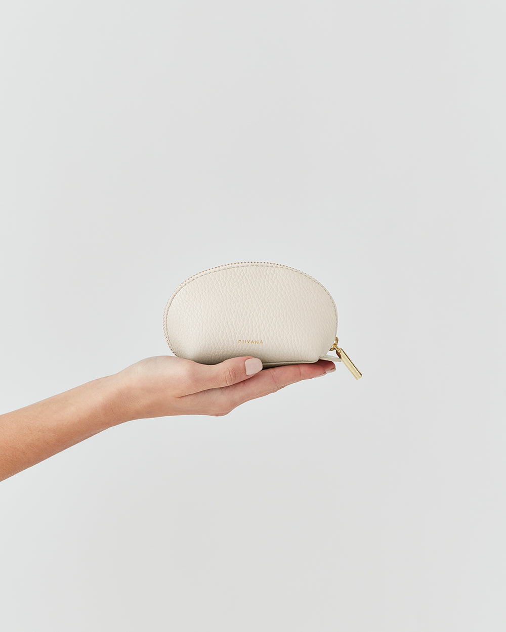Hand holding a small zippered pouch against a plain background.
