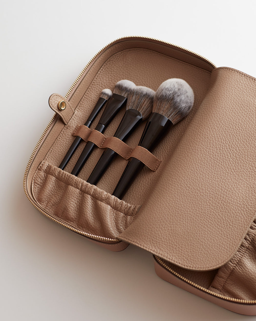 Open makeup bag with several brushes inside.