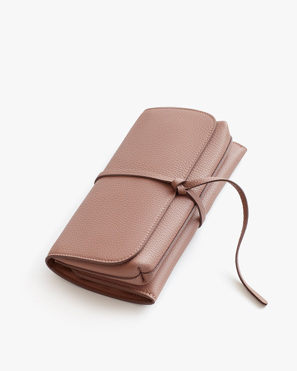 Travel Beauty Roll Closed wallet with a wraparound tie on a plain background.