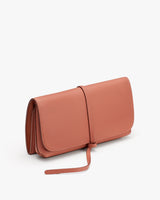 A handbag with a strap standing against a plain background.