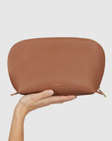 Hand holding a leather pouch with zipper closure.