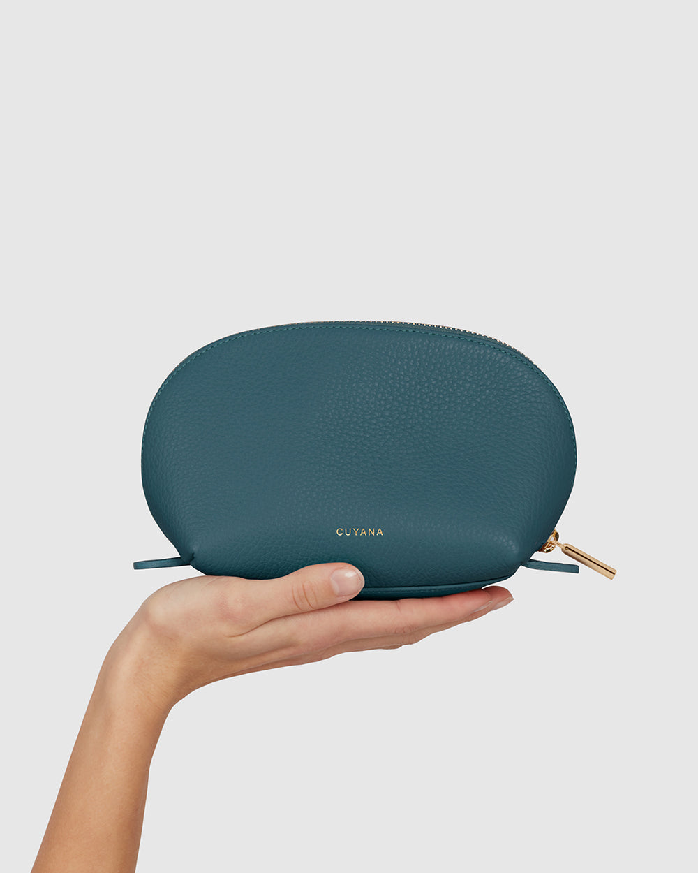 Travel Case Set Hand holding a small zippered case with brand name.