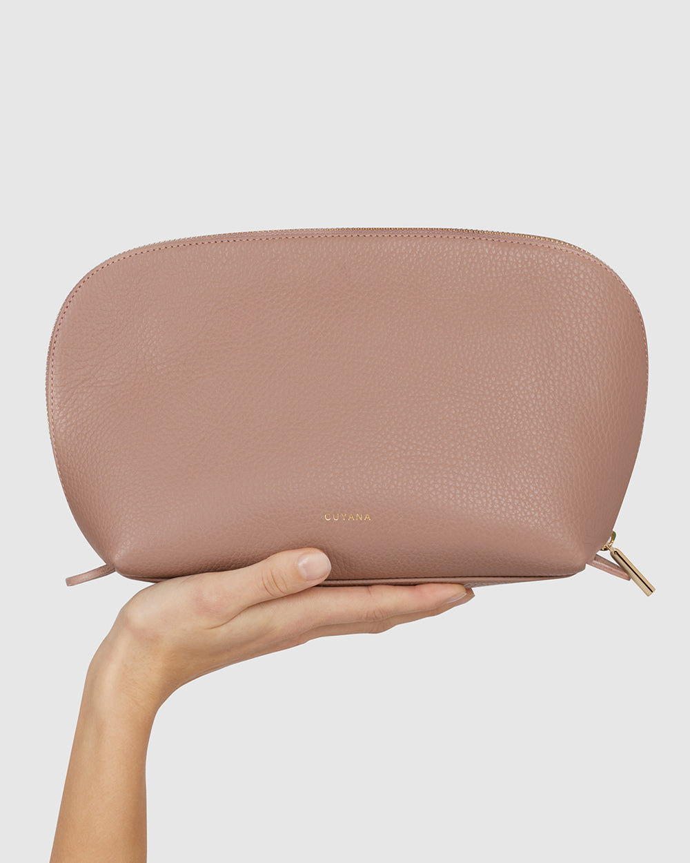 Hand holding a textured clutch with a zipper closure.