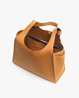 Handbag standing upright with top opening visible and a zippered compartment inside.