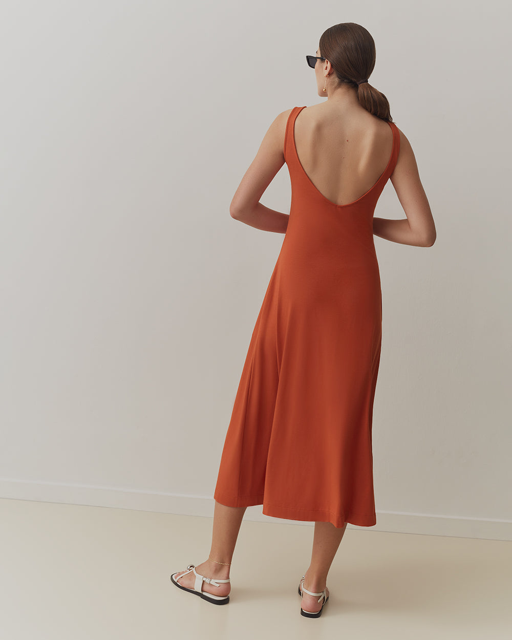 Duo Midi Dress Woman wearing a sleeveless dress and sandals, facing away.
