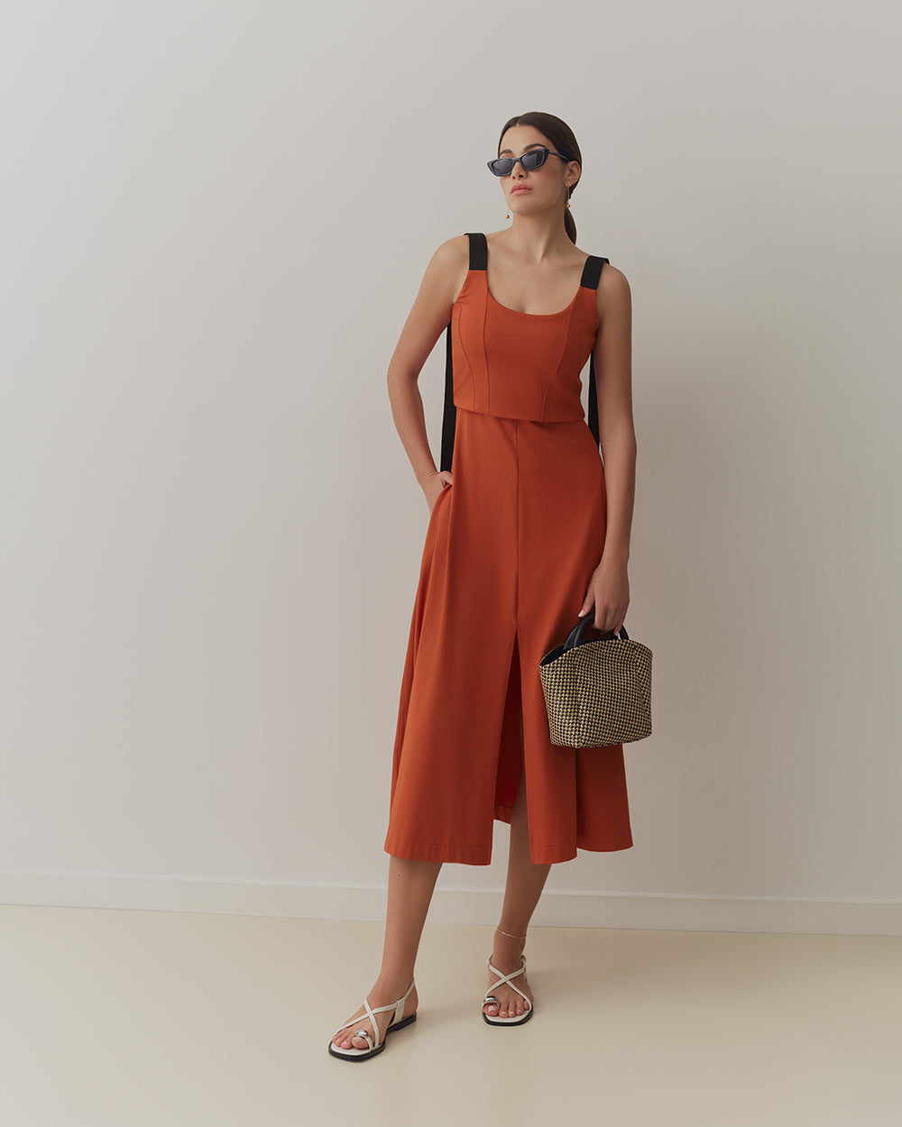 Duo Midi Dress Person in a sleeveless dress holding a handbag, wearing sunglasses.