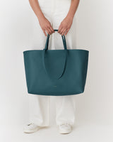 Person holding large tote bag, wearing white pants and white shoes.