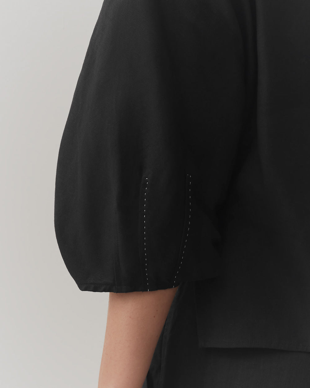 Close-up of a person's sleeve with decorative stitching.