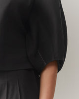 Close-up of a person's arm in a short-sleeved top.