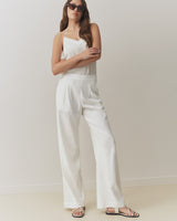 Woman in sleeveless top and pants standing with arms crossed