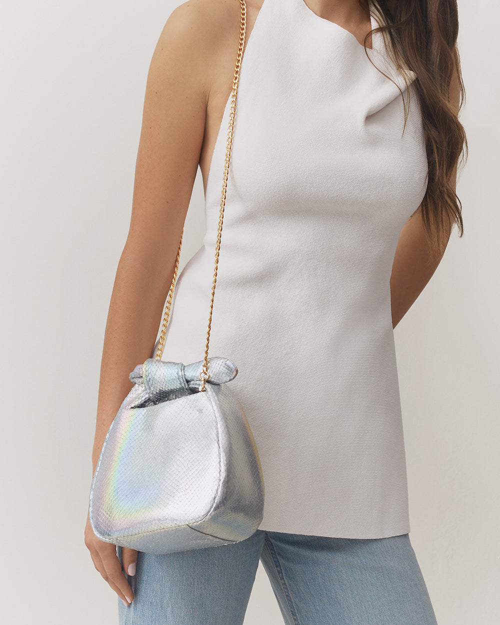 Mini Bow Bag (Snake) Person wearing a sleeveless top, jeans, and carrying a snake-embossed leather bag with a chain strap.