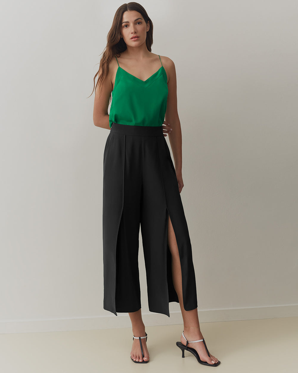 Silk Brisa Pant Woman wearing a sleeveless top and wide-leg pants with side slits, standing in a plain room