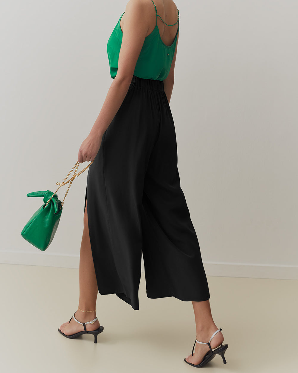 Silk Brisa Pant Person wearing a sleeveless top and wide-leg pants holding a handbag.