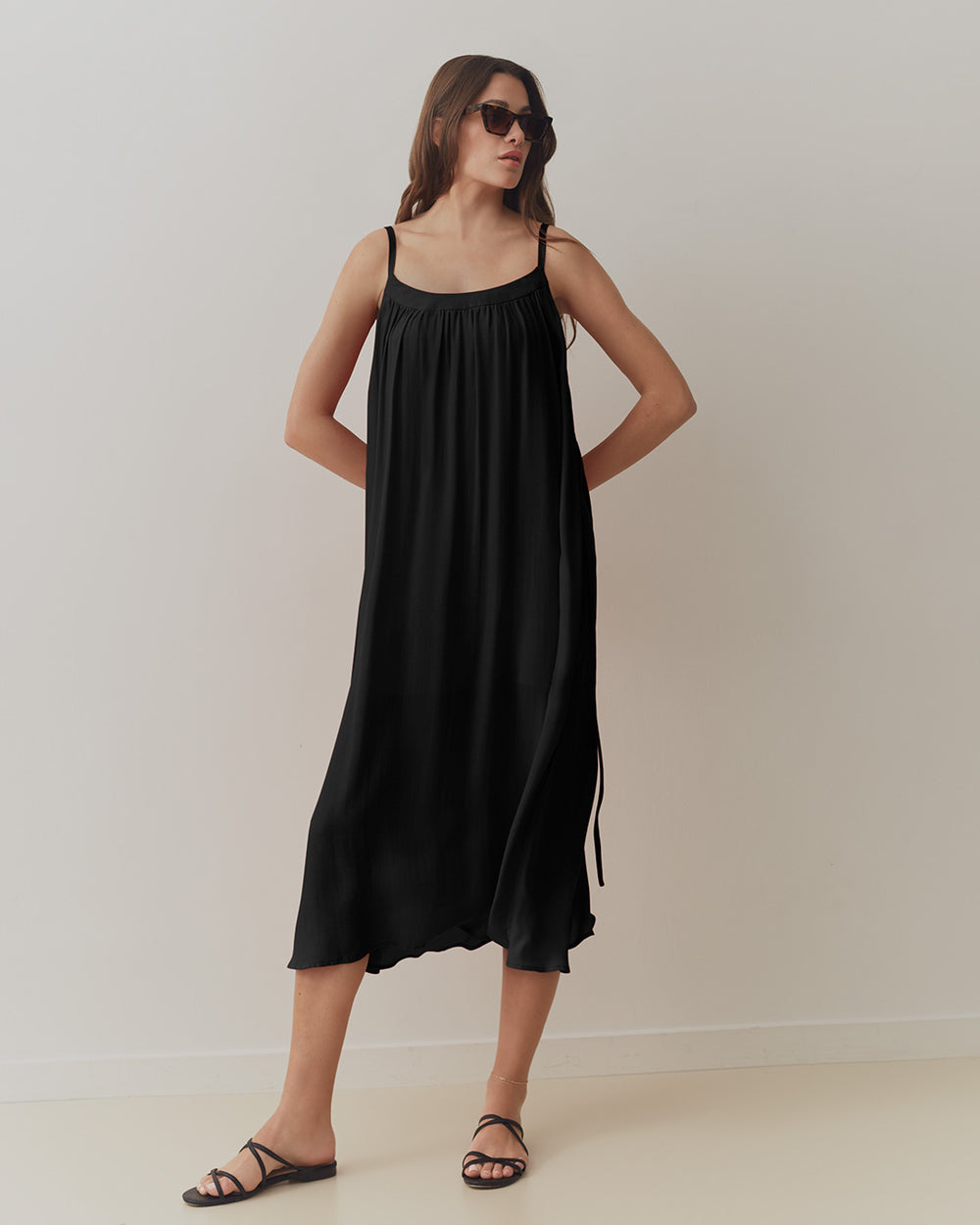 Woman in dress and sunglasses standing in a room.