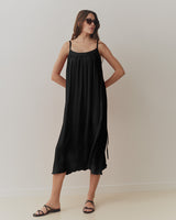 Woman in dress and sunglasses standing in a room.