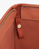 Open bag with gold zipper and leather strap inside.