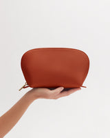 Person holding a small pouch against a plain background.
