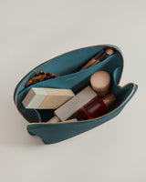 Makeup bag open with cosmetics and brushes inside.