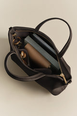 Open handbag with books, a wallet, and a small bottle inside