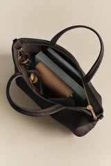 Open handbag with books, a wallet, and a small bottle inside