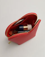 Open cosmetic pouch with various makeup items inside.