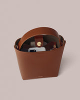 Open handbag with items inside, showing a phone and strap with button closure.