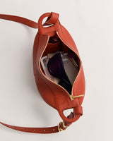 Open handbag with sunglasses, phone, and small items inside.