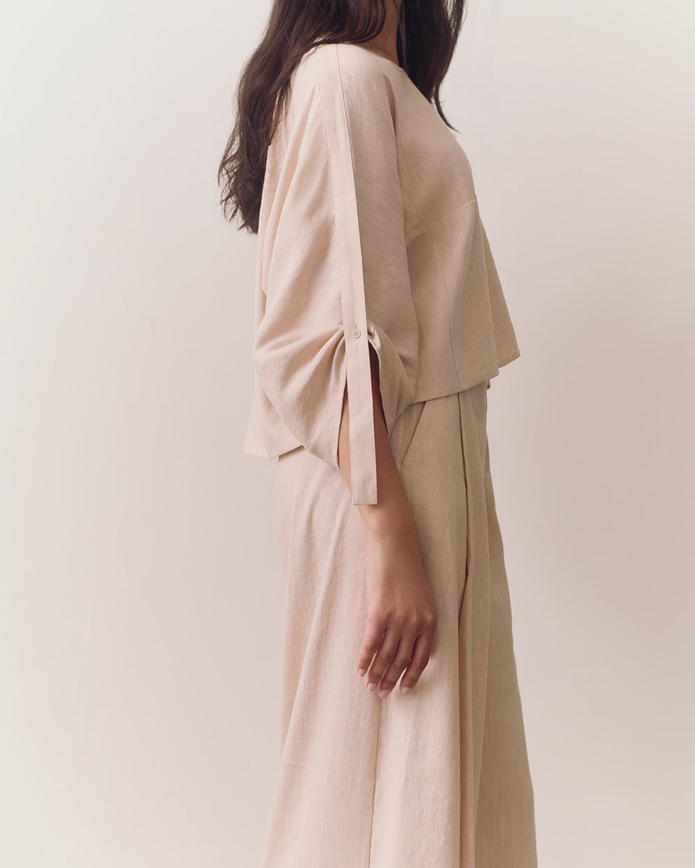 Linen Adjustable Sleeve Top Person wearing loose top and wide-leg pants standing against plain backdrop