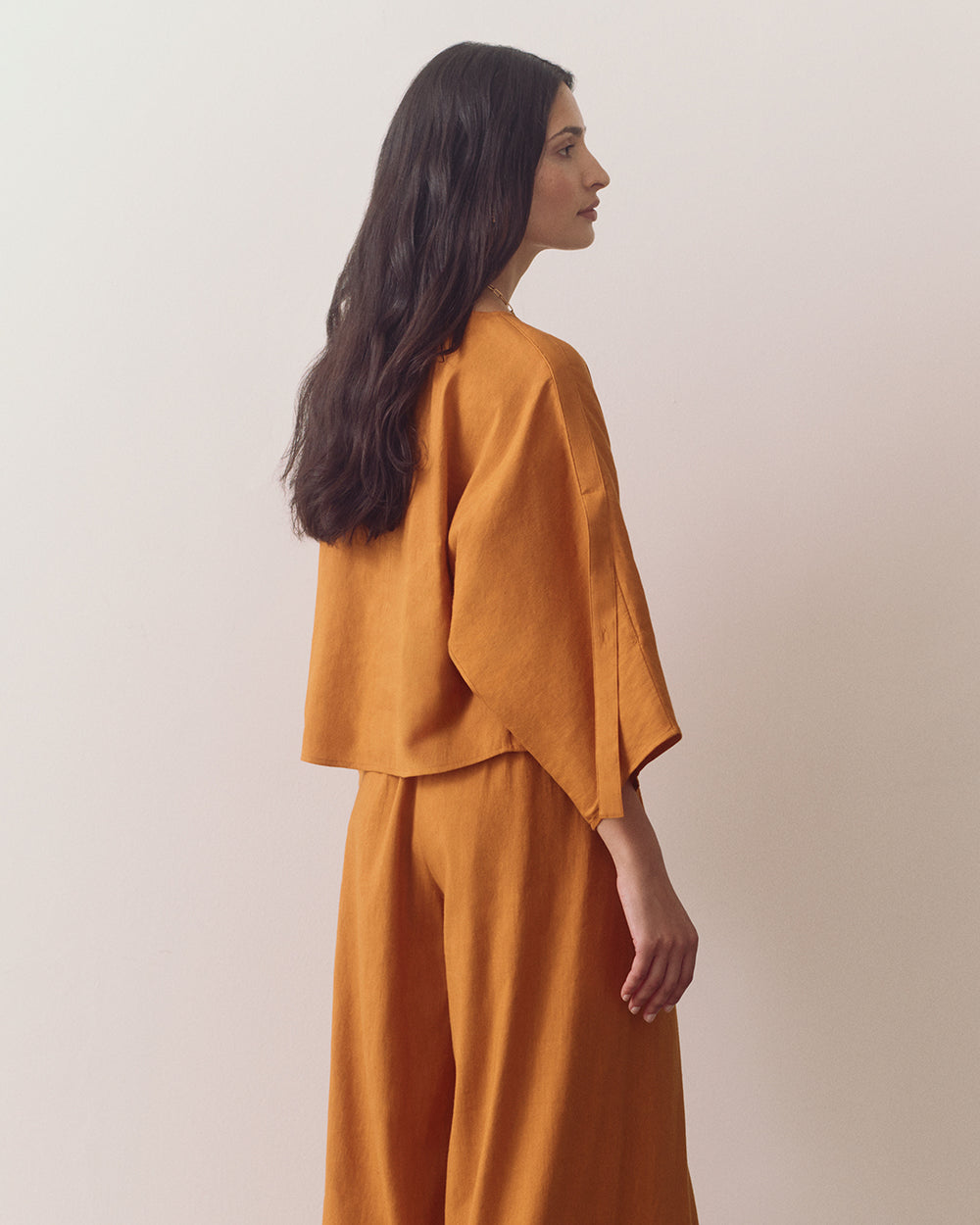 Person in loose top and wide-leg pants, looking sideways