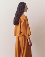 Person in loose top and wide-leg pants, looking sideways