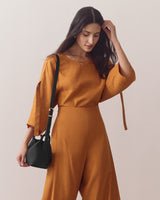 Person in a matching outfit holds a shoulder bag.