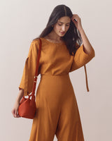 Person in a matching outfit holds a shoulder bag.