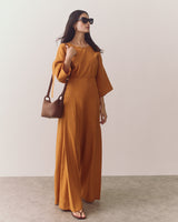 Woman in wide-leg pants holding a small basket bag and wearing sunglasses.