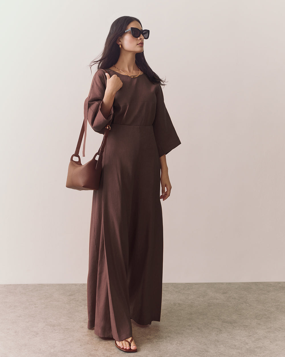 Person wearing loose top and wide-leg pants standing against plain backdrop