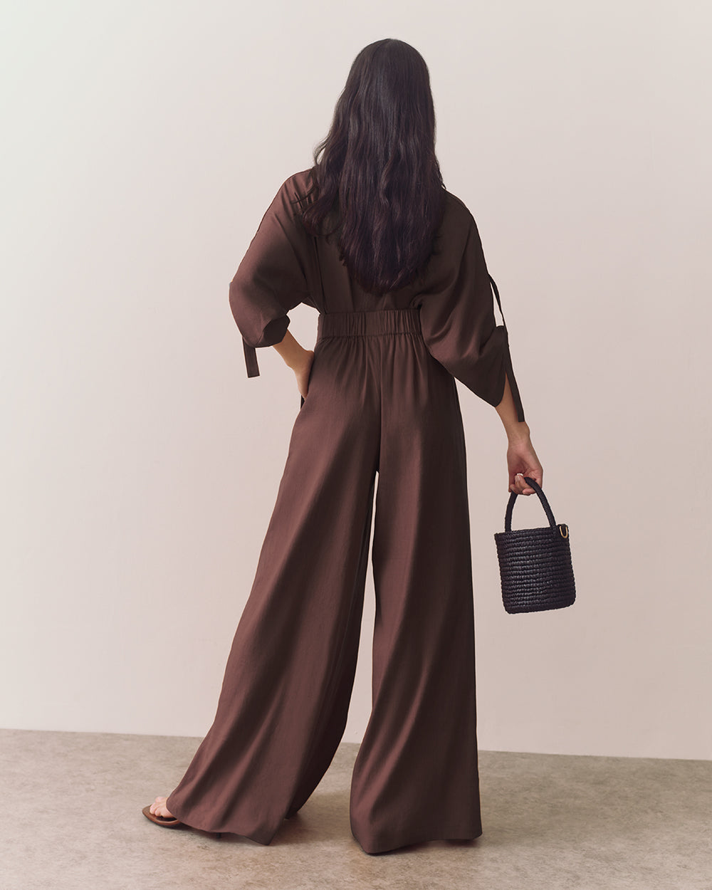 Person wearing wide leg pants holding a small croc-embossed leather bag