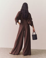 Person wearing wide leg pants holding a small croc-embossed leather bag