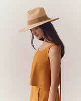 Person wearing a sleeveless dress and wide-brimmed hat looking down